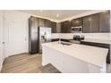 Modern kitchen features stainless steel appliances, dark wood cabinets, and a white countertop island for food preparation at 1961 S Haleyville Way, Aurora, CO 80018