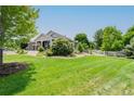 Expansive lawn and mature trees surround this lovely home with a charming white fence and beautiful curb appeal at 7126 E 162Nd Ct, Brighton, CO 80602