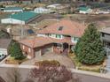 Aerial view of a spacious home with a tile roof, a three-car garage, and a circular driveway surrounded by lush landscaping at 132 Loveland Way, Golden, CO 80401