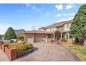 Eye-level shot of a home with a three-car garage, beautiful landscaping, and brick design elements at 132 Loveland Way, Golden, CO 80401