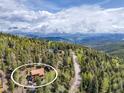 Beautiful aerial view showing the home nestled in a mountain with surrounding trees, views, and a long gravel driveway at 1000 Lodgepole Dr, Evergreen, CO 80439