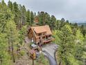 Elevated aerial view showcasing the log home's exterior, landscaping, surrounding trees, and driveway at 1000 Lodgepole Dr, Evergreen, CO 80439