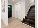 Bright entryway featuring light wood floors, a dark front door, and a staircase at 6501 Welch Ct, Arvada, CO 80004