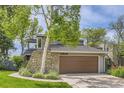Front exterior of home with stone accents, lush landscaping, and an attached garage at 1540 W Briarwood Ave, Littleton, CO 80120