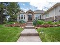 Inviting front entrance with stone accents, lush landscaping, and a walkway leading to the wood and glass front door at 1030 Timbercrest Dr, Castle Pines, CO 80108