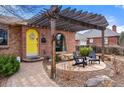 Inviting front porch with brick detail, a yellow door with wreath, and a covered seating area with stylish chairs at 2576 Krameria St, Denver, CO 80207