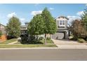 Charming two-story home with a two-car garage, well-maintained lawn, and mature trees on a sunny day at 25548 E Fair Dr, Aurora, CO 80016