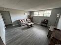 Cozy living room featuring gray walls, wood-look flooring, a comfortable couch, and natural light from the window at 9440 E Girard Ave # 1, Denver, CO 80231