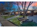 Beautiful exterior with manicured lawn, mature tree, and inviting walkway at sunset at 2694 S Krameria St, Denver, CO 80222