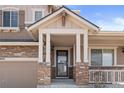 Close-up of the front porch featuring stone pillars, a black front door, and manicured landscaping at 20145 E Fair Ln, Centennial, CO 80016