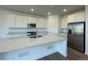 Modern kitchen with white cabinetry, stainless steel appliances, and a spacious island at 767 Raindance St, Erie, CO 80516
