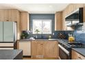 Bright kitchen featuring stylish wooden cabinets, modern appliances, and chic blue tile backsplash at 815 S Jersey St, Denver, CO 80224
