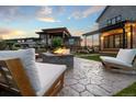 Inviting backyard with a stone fire pit, modern seating, a covered patio, and lush green landscaping at 27250 E Nova Cir, Aurora, CO 80016