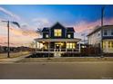 Inviting two-story home with covered front porch and manicured landscaping at sunset at 5965 Hanover St, Denver, CO 80238