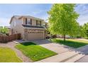 Charming two-story home featuring a well-manicured lawn, mature tree, and a two-car garage with a brick accent at 13180 Jasmine St, Thornton, CO 80602
