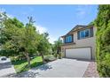 Lovely two-story home featuring a two-car garage, green lawn, and mature trees at 8725 Meadowlark Cir, Highlands Ranch, CO 80126