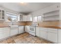 Quaint kitchen with white cabinets, wood countertops, a farmhouse sink, and stainless steel appliances at 2515 Ames St, Edgewater, CO 80214