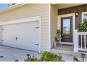 Close up of a home's front door, garage and covered porch with a decorative wreath and tidy landscaping at 1063 Gianna Ave, Fort Lupton, CO 80621