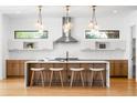 Modern kitchen boasts a large island with seating, designer lighting, stainless steel appliances, and bright white backsplash at 1241 S Garfield St, Denver, CO 80210
