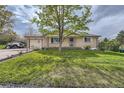 Lovely front yard featuring lush green grass and a well-maintained brick home exterior with a car in the driveway at 755 Braun St, Lakewood, CO 80401
