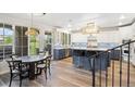 Elegant eat-in kitchen with a blue island, pendant lighting, white cabinetry, and access to the covered patio at 9151 E Harvard Ave, Denver, CO 80231