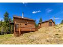 Wood-sided cabin featuring stairs and a deck that offers scenic views, complemented by an adjacent outbuilding at 33606 Gap Rd, Golden, CO 80403