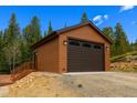 Detached garage with automatic door and siding, complemented by lush trees at 33606 Gap Rd, Golden, CO 80403