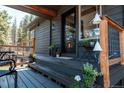 Charming home entrance featuring a wooden deck, stylish plants and a modern glass door at 32663 Donna Dr, Conifer, CO 80433