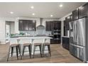 Stylish kitchen boasts a central island with seating, stainless appliances, and dark wood cabinets at 1677 Meagan Way, Erie, CO 80516
