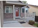Inviting front porch with brick accents, offering a cozy spot to relax and enjoy the neighborhood view at 6123 S Quemoy Way, Aurora, CO 80015