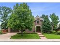 Beautiful brick home featuring an attached two-car garage, mature trees, and lovely landscaping at 50 S Eudora St, Denver, CO 80246