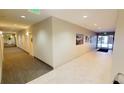 Well-lit hallway featuring neutral walls, carpeted floors, artwork, and visible exit signs at 1144 Rockhurst Dr # 105, Highlands Ranch, CO 80129