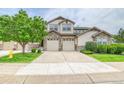 Inviting townhome showcases stone accents, a lush green lawn, and an attached two-car garage at 23070 York Ave, Parker, CO 80138