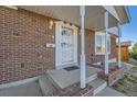 Inviting brick home facade featuring a classic white metal security door and a covered porch at 8062 Kalamath St, Denver, CO 80221