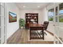 Bright home office featuring French doors, hardwood floors, a window, and built in book shelves at 6692 S Robertsdale Way, Aurora, CO 80016