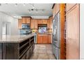 Close up of kitchen featuring wood cabinets, granite countertops, wine storage, and stainless appliances at 13456 Via Varra # 428, Broomfield, CO 80020