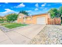 A ranch-style home boasts a driveway and a well-kept lawn with rock landscaping at 14595 Robins Dr, Denver, CO 80239