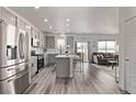 Bright, open kitchen with stainless steel appliances and a center island with seating, flowing into the living room at 515 Bridger Ave, Fort Lupton, CO 80621