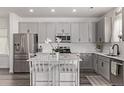 Well-lit kitchen boasts island seating, stainless steel appliances, and stylish gray cabinetry at 515 Bridger Ave, Fort Lupton, CO 80621