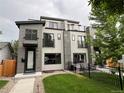 Modern home featuring gray siding, sleek black trim, and a cozy front yard with lush green grass at 2473 S Cherokee St, Denver, CO 80223