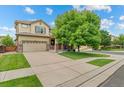 Traditional two-story home featuring a two-car garage and manicured lawn with mature landscaping at 10197 Quintero St, Commerce City, CO 80022