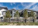 Backyard view of modern home featuring a dark wood fence, gray exterior, and mature trees at 7125 Skygazer St, Castle Pines, CO 80108