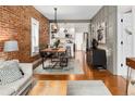 Open living area featuring hardwood floors, exposed brick accent wall, modern furniture, and bright lighting at 1452 S Logan St, Denver, CO 80210
