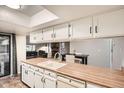 Bright kitchen with wood counters, white cabinets, and stainless steel appliances and views into dining and living area at 9483 W 89Th Cir, Broomfield, CO 80021