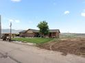 Charming brick home featuring a well-maintained lawn, mature tree, and unique mining cart decor at 16535 W 79Th Dr, Arvada, CO 80007