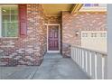 Close-up of the brick front porch with a wreath-adorned door and white railing at 23580 E Portland Way, Aurora, CO 80016