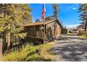 Charming home featuring a front porch, wood siding, and a gravel driveway surrounded by lush trees at 31084 Kings Valley Dr, Conifer, CO 80433