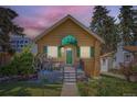Charming single-story home featuring a quaint front porch, green shutters, and landscaped garden at 1559 Elm St, Denver, CO 80220