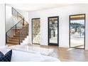 The home's entryway features light wood floors, a staircase with black railings, and modern design touches at 2442 Fox View Trl, Franktown, CO 80116