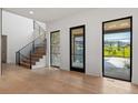 Bright foyer featuring wood floors, an elegant staircase, and views of the front yard at 2442 Fox View Trl, Franktown, CO 80116